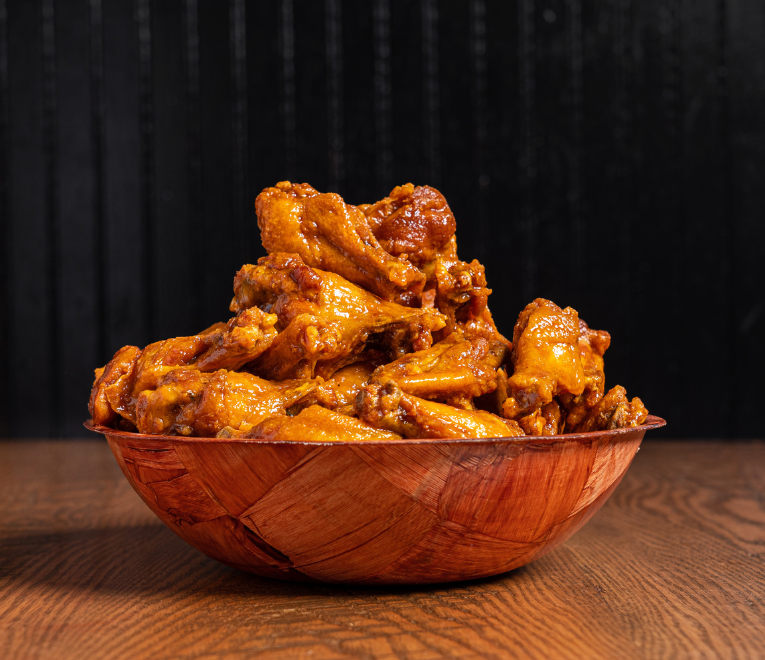 A wooden bowl filled with chicken wings.